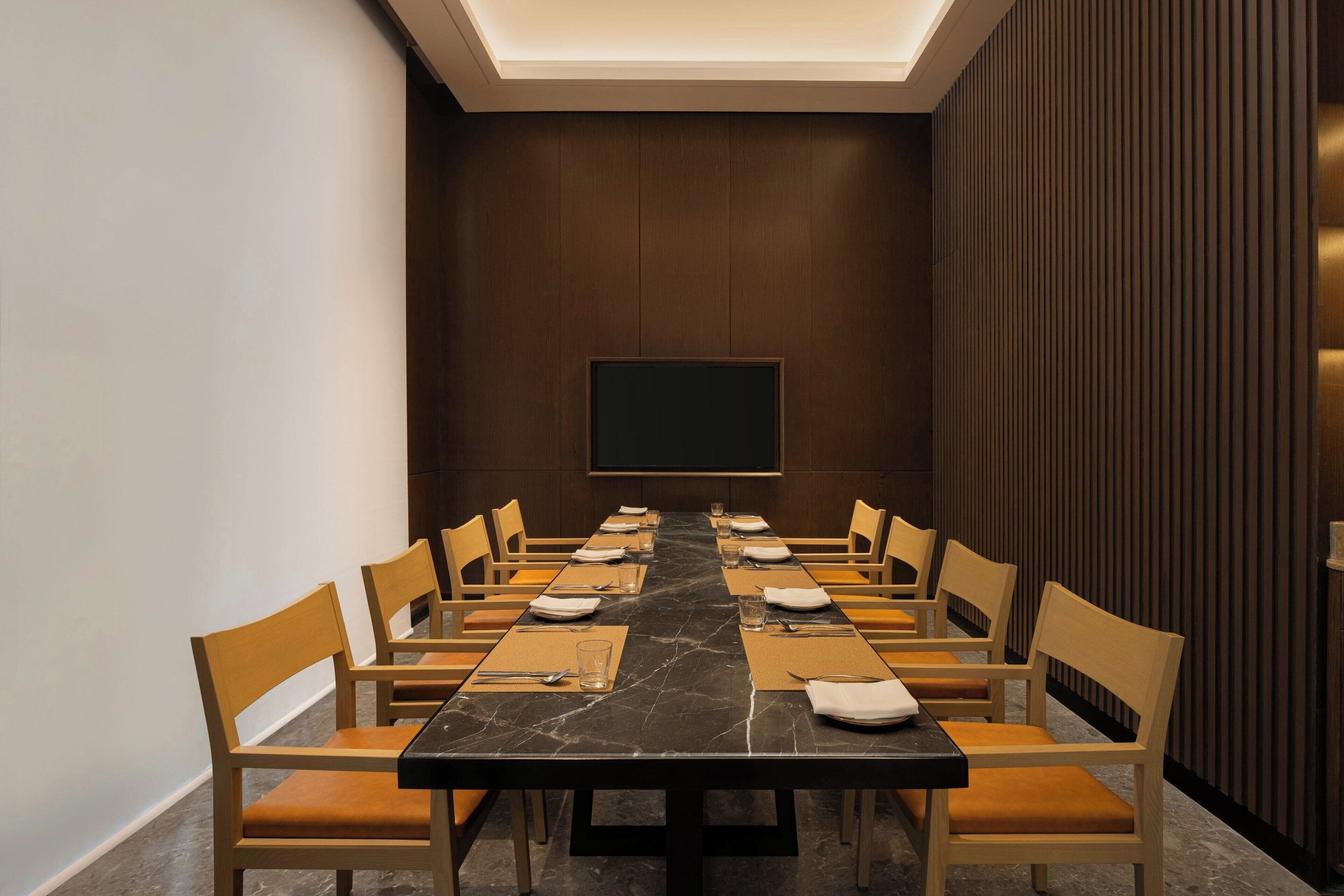 A conference room with a long table, chairs, and a flat-screen TV on the wall.