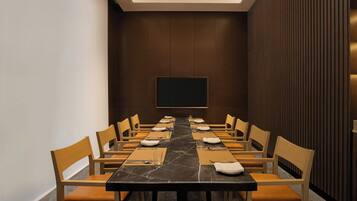 A conference room with a long table, chairs, and a flat-screen TV on the wall.