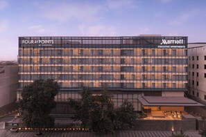 Ein modernes Hotelgebäude mit Glasfassade, mit der Aufschrift "Four Points by Sheraton" und "Marriott Executive Apartments".