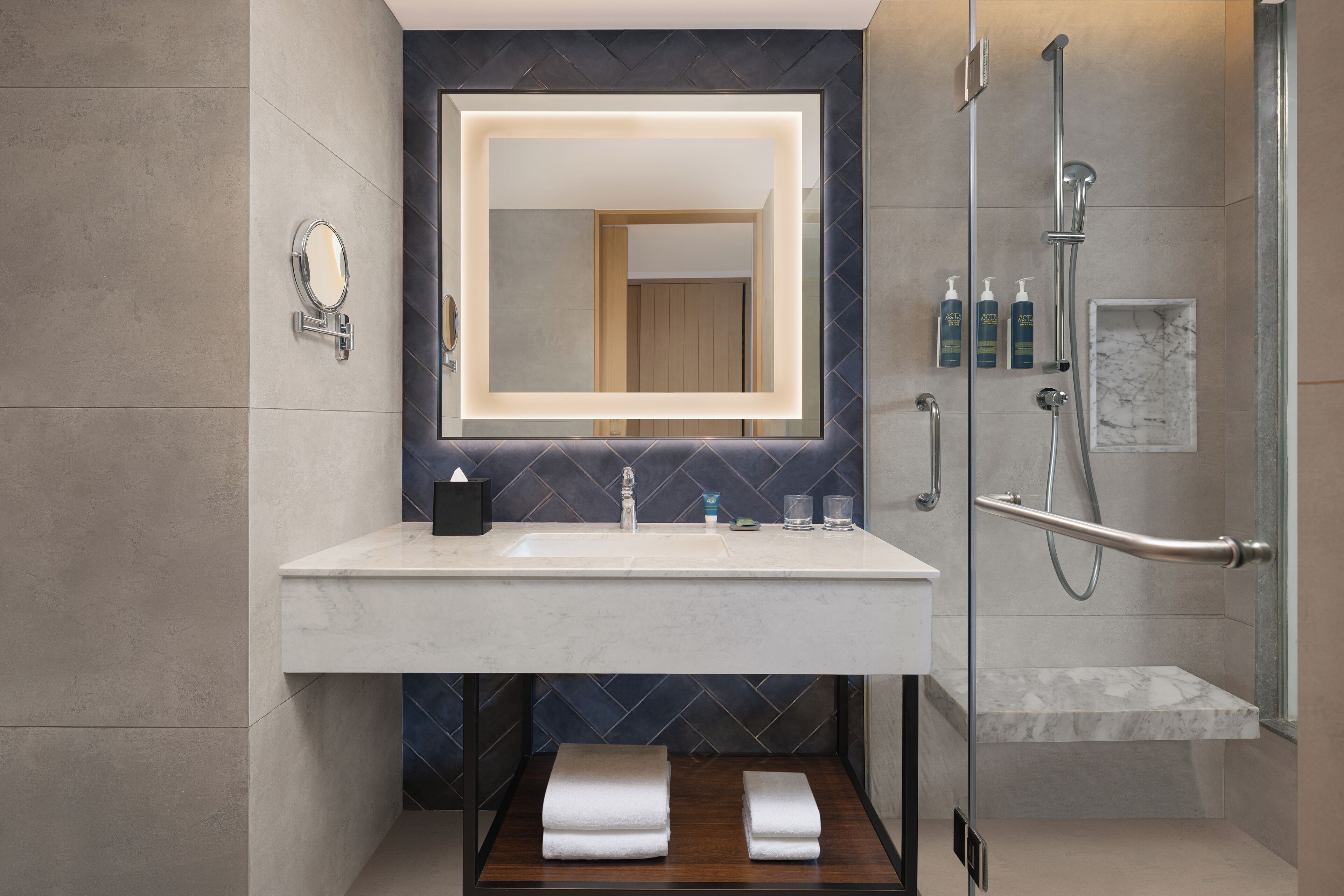 Een moderne badkamer met een grote spiegel, een wastafel en een douchehoek.