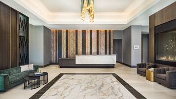 Um lobby moderno com balcão de recepção, sofás, lustre e lareira.