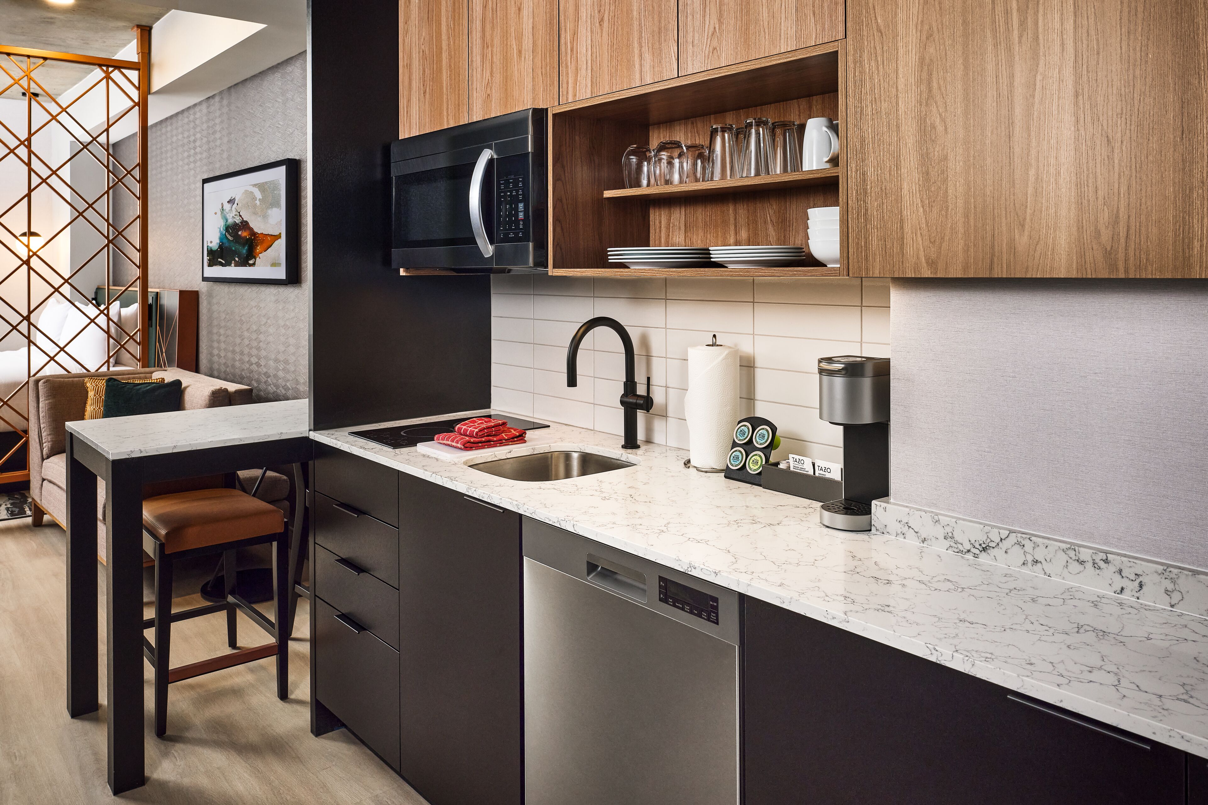 A modern kitchen with a built-in dishwasher, a microwave, and a coffee machine.