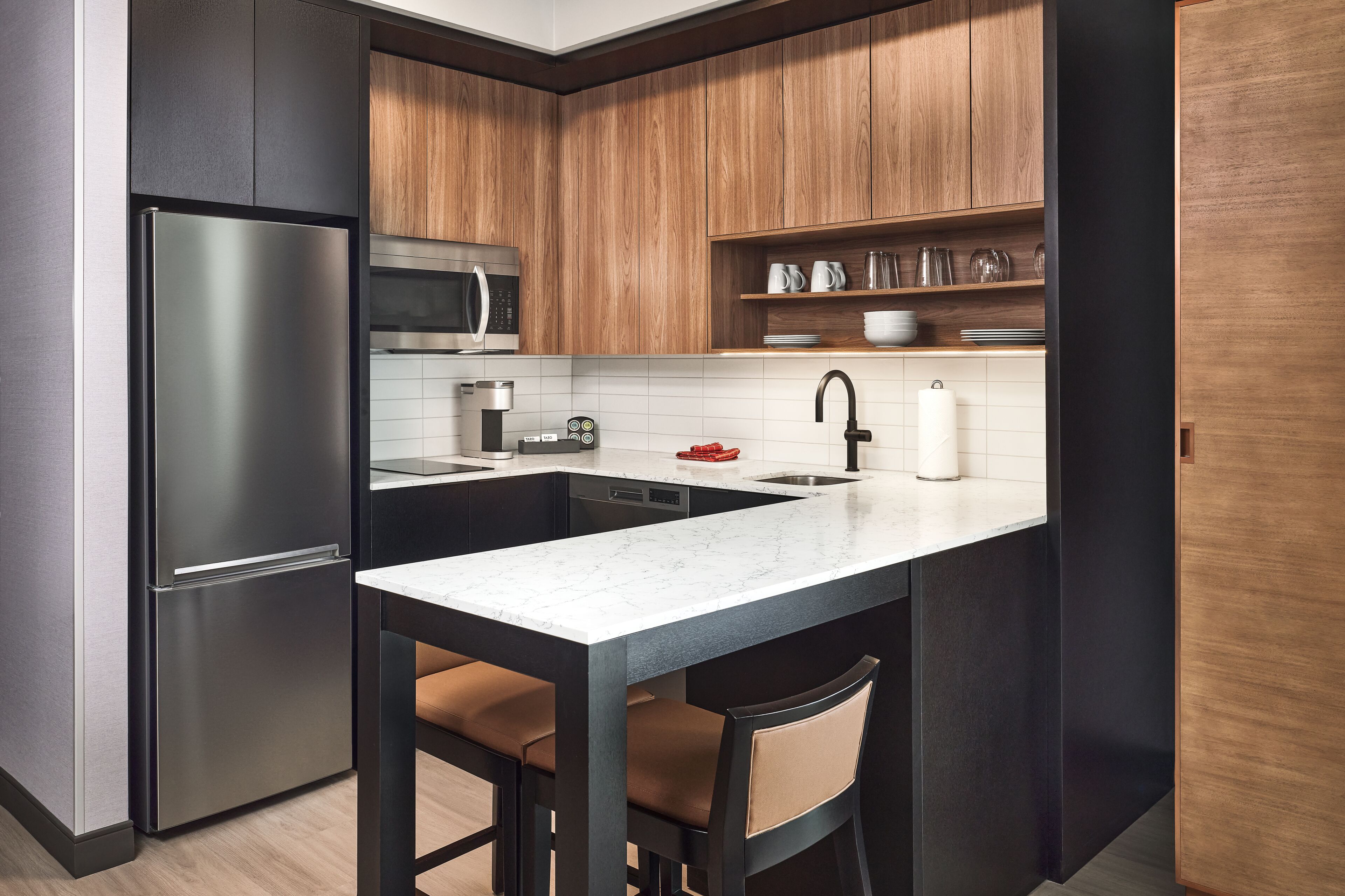 A compact kitchen with a refrigerator, microwave, and a sink with a faucet.