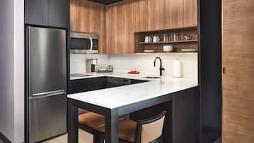 A compact kitchen with a refrigerator, microwave, and a sink with a faucet.