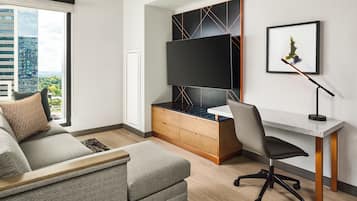 A modern living room with a sofa, a desk, a chair, a TV, and a framed picture on the wall.