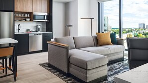 Una sala moderna con un sofá, un comedor y una cocina equipada con microondas.
