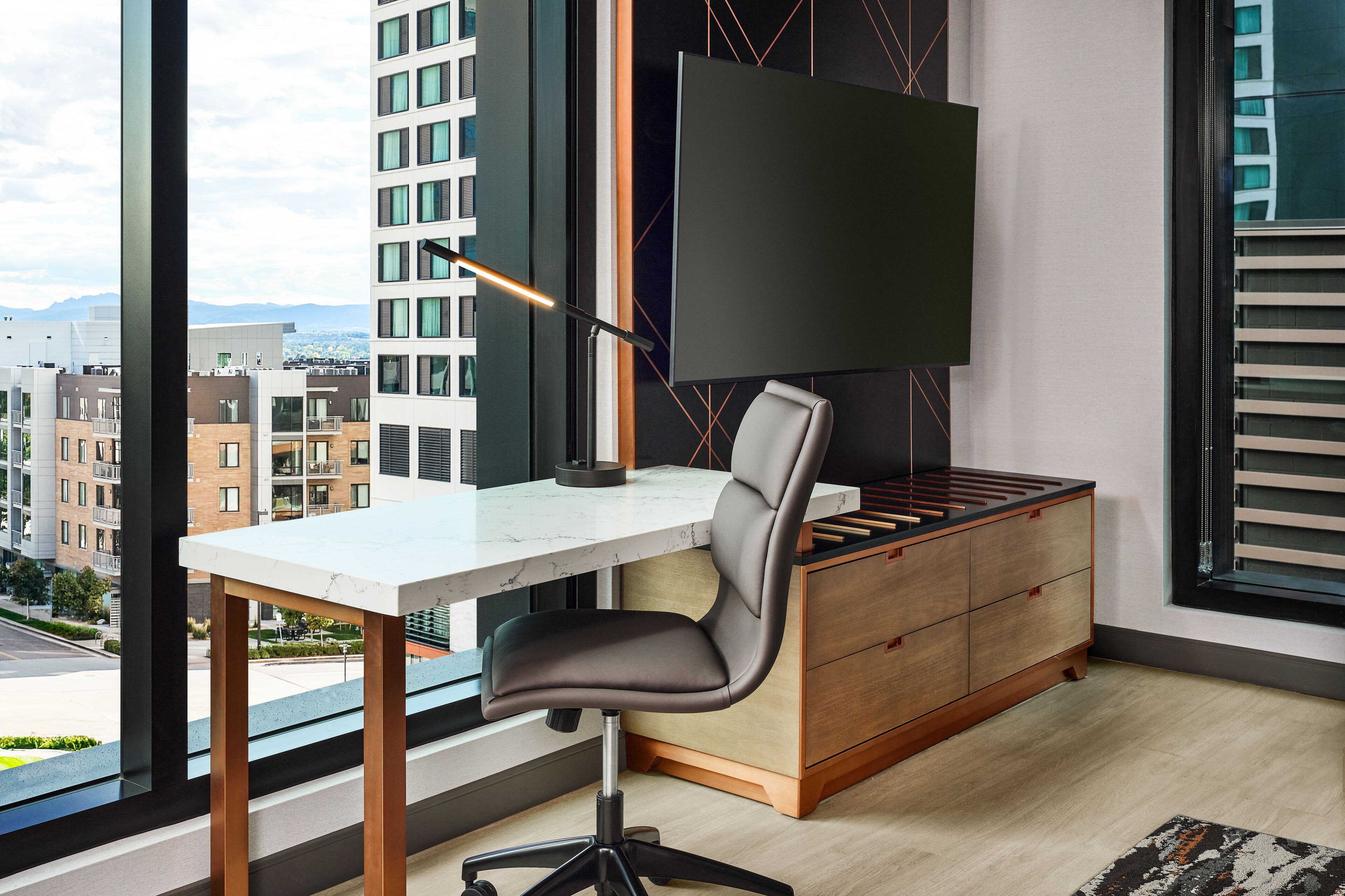A modern office space with a desk, chair, and TV.
