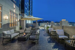 An outdoor patio with wicker furniture, a fire pit, and a TV screen. - Residence Inn By Marriott Montgomery Downtown (Montgomery)