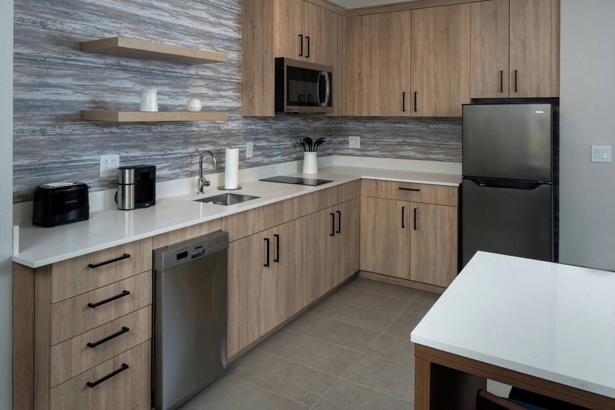 Una cocina moderna con armarios de madera, un refrigerador de acero inoxidable, un microondas y un lavavajillas.