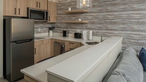 A modern kitchen with a built-in microwave, stainless steel refrigerator, and a dishwasher. There are wooden cabinets, a white countertop, and a marble backsplash. - Residence Inn By Marriott Montgomery Downtown (Montgomery)