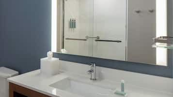 A bathroom with a white sink, a mirror, and a glass shower enclosure.