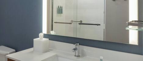 A bathroom with a white sink, a mirror, and a glass shower enclosure.