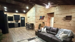 A cozy cabin interior with a wooden interior, a dining area, and a living room with a sofa and rug. - New Cozy Country barndominium located in Leitchfield, KY. (Leitchfield)