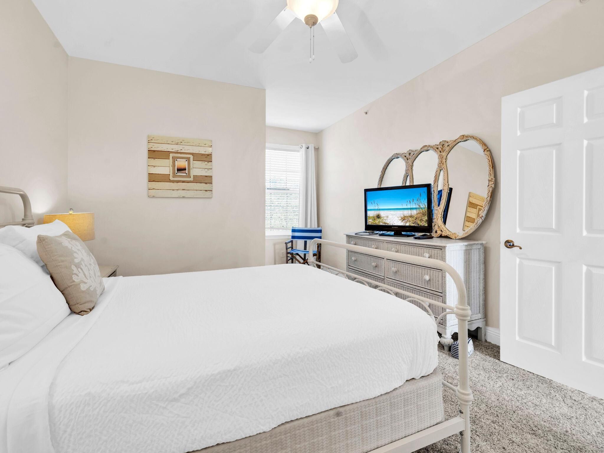 Une chambre à coucher avec un lit, une télévision, une commode et une porte.