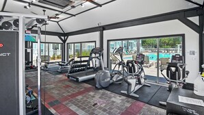 A gym with exercise equipment, a treadmill, and a view of a swimming pool. - The Village 622 (Santa Rosa Beach)