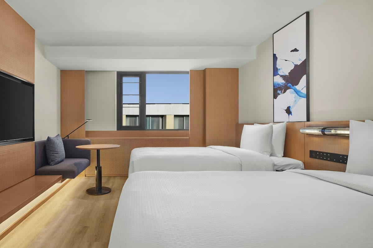 Une chambre d’hôtel moderne avec un grand lit, un canapé, une petite table et un téléviseur.