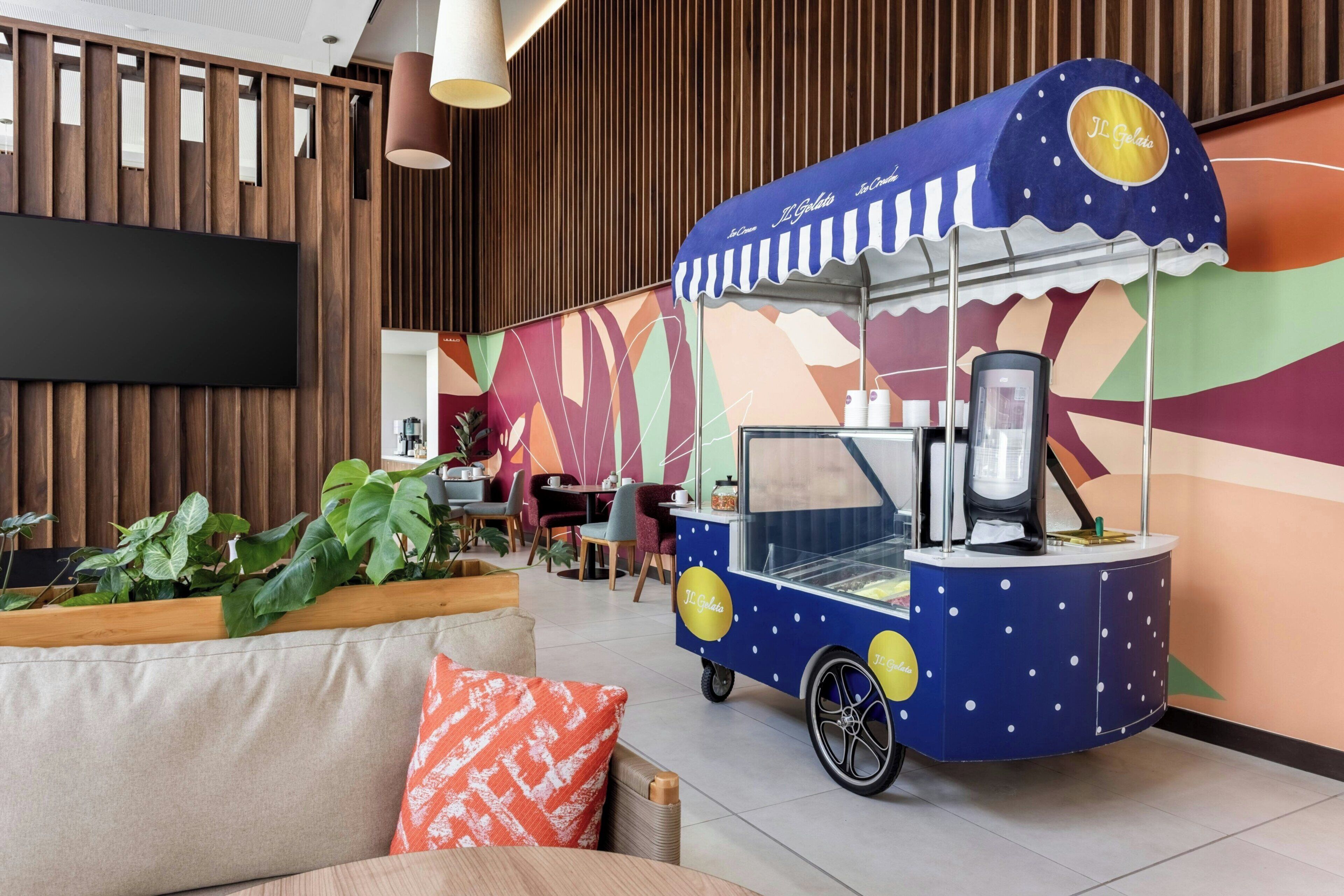 Un carrito de comida con un diseño llamativo, una zona de estar con cojines y una pared con listones de madera verticales.