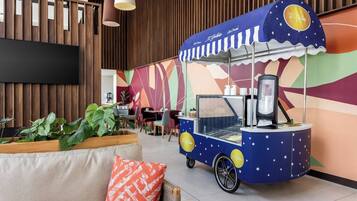 Un carrito de comida con un diseño llamativo, una zona de estar con cojines y una pared con listones de madera verticales.