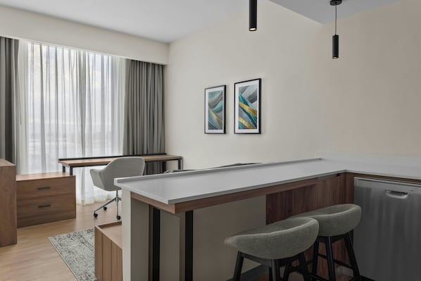 Una cocina moderna con barra, armarios de madera y un amplio ventanal con cortinas.