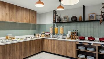 Een keuken met houten kastjes, een betegelde spatwand en divers keukengerei.