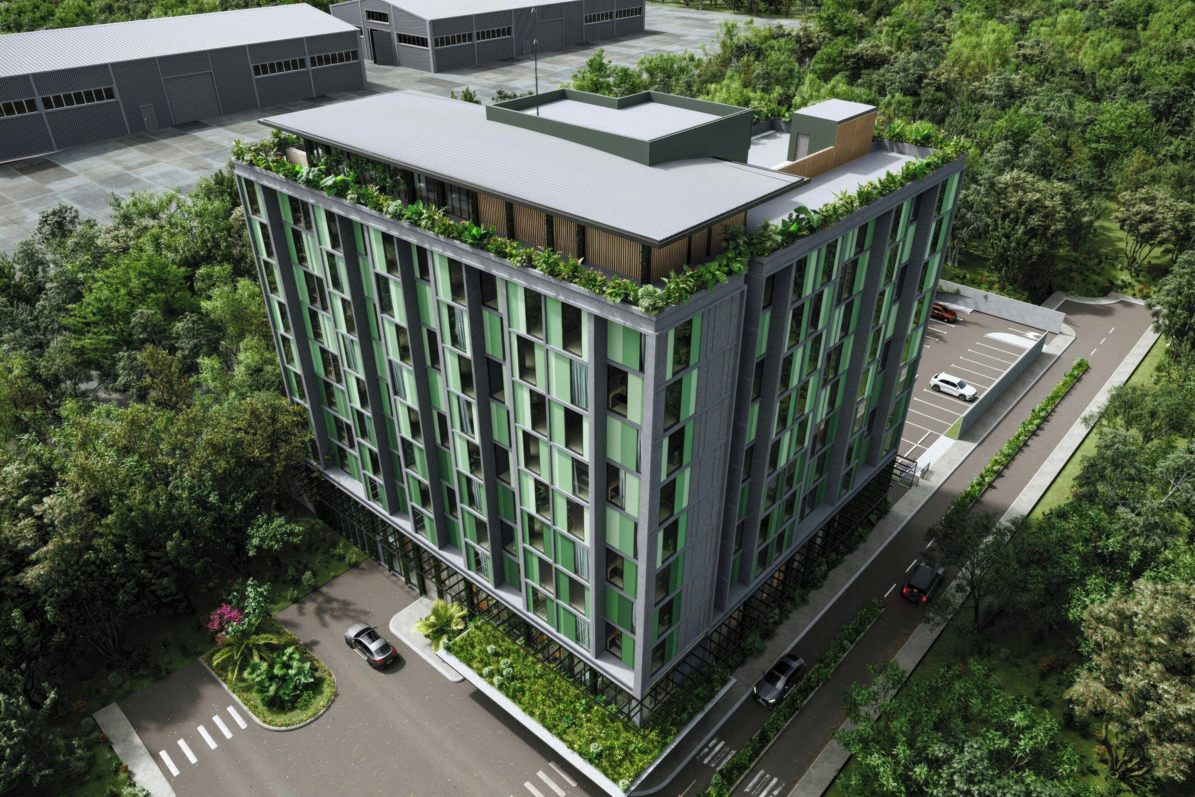 A modern building with a rooftop garden, surrounded by greenery.