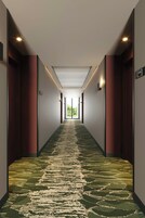 Un pasillo con alfombra estampada, puertas a ambos lados y un letrero que indica la habitación número 204.