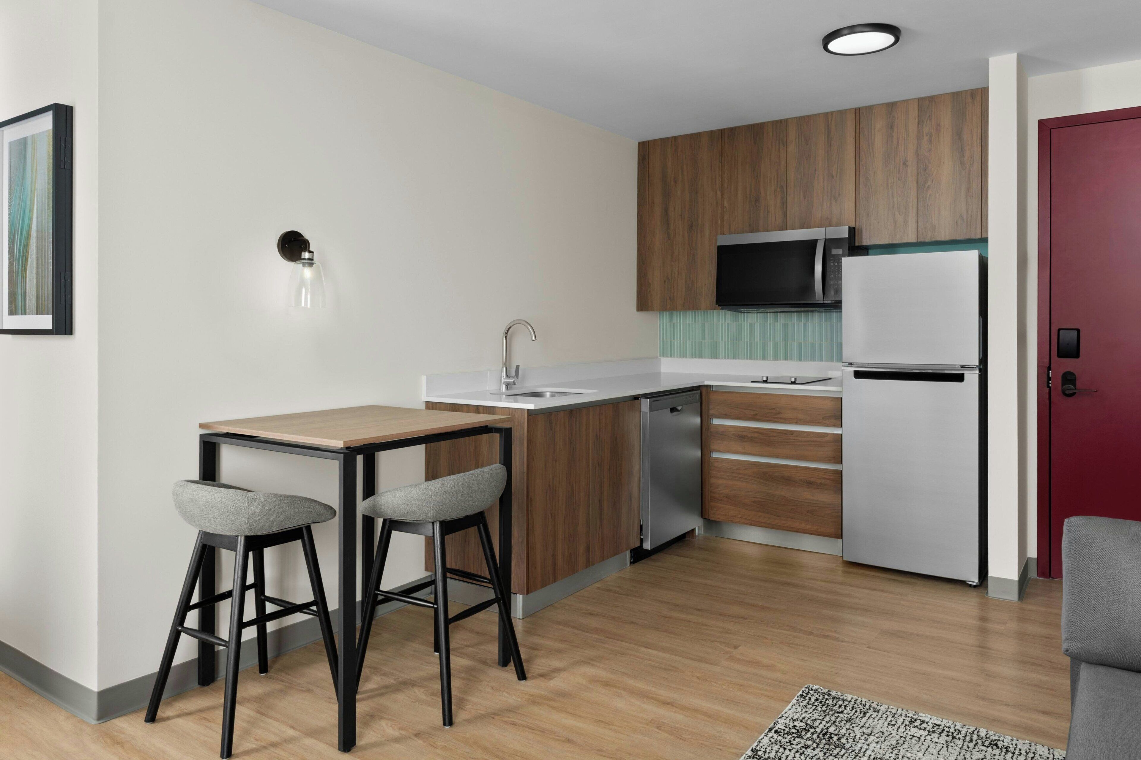 A modern kitchen with a wooden countertop, stainless steel appliances, and two bar stools.