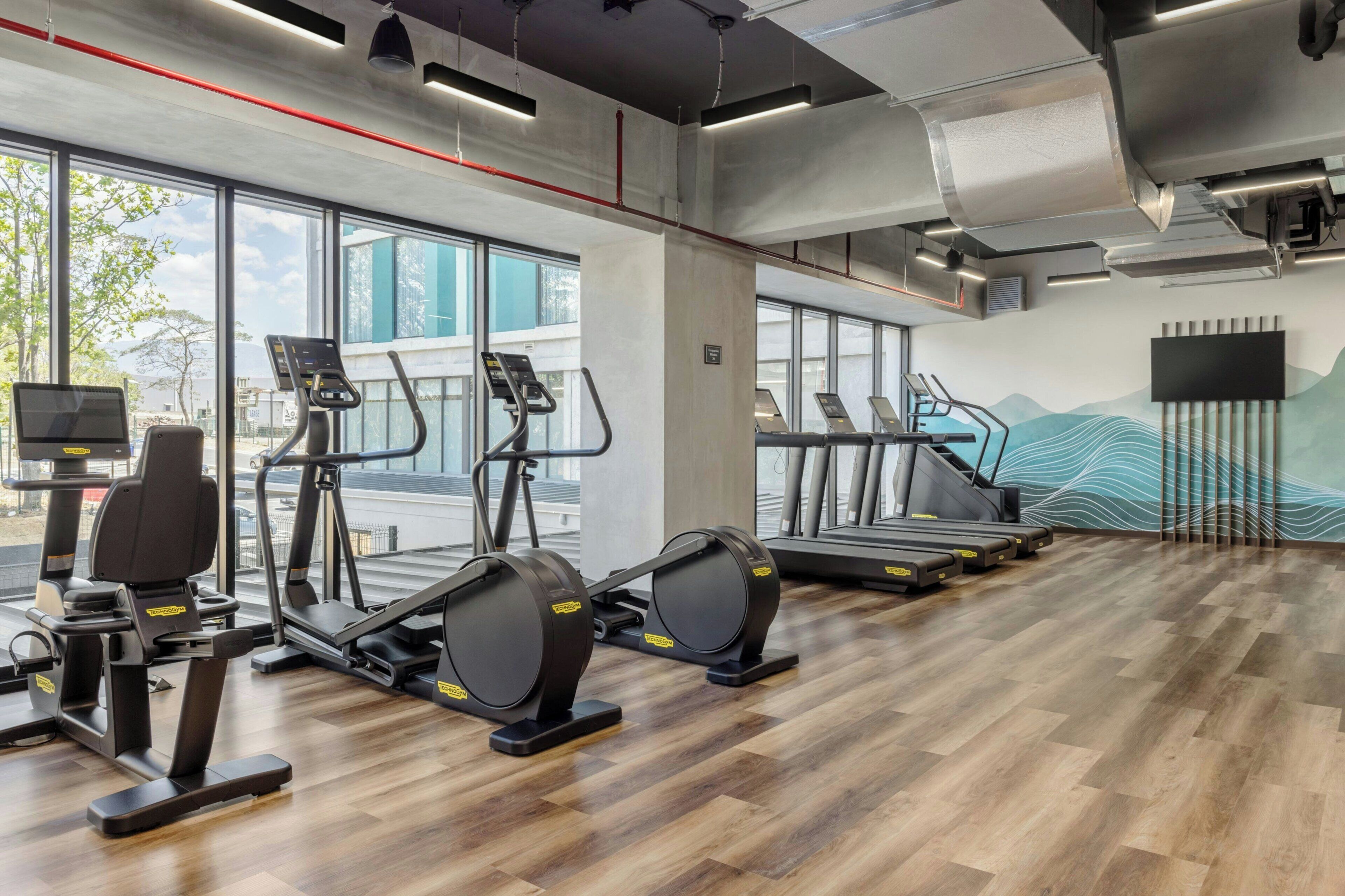 A gym with treadmills, elliptical machines, and weight equipment.