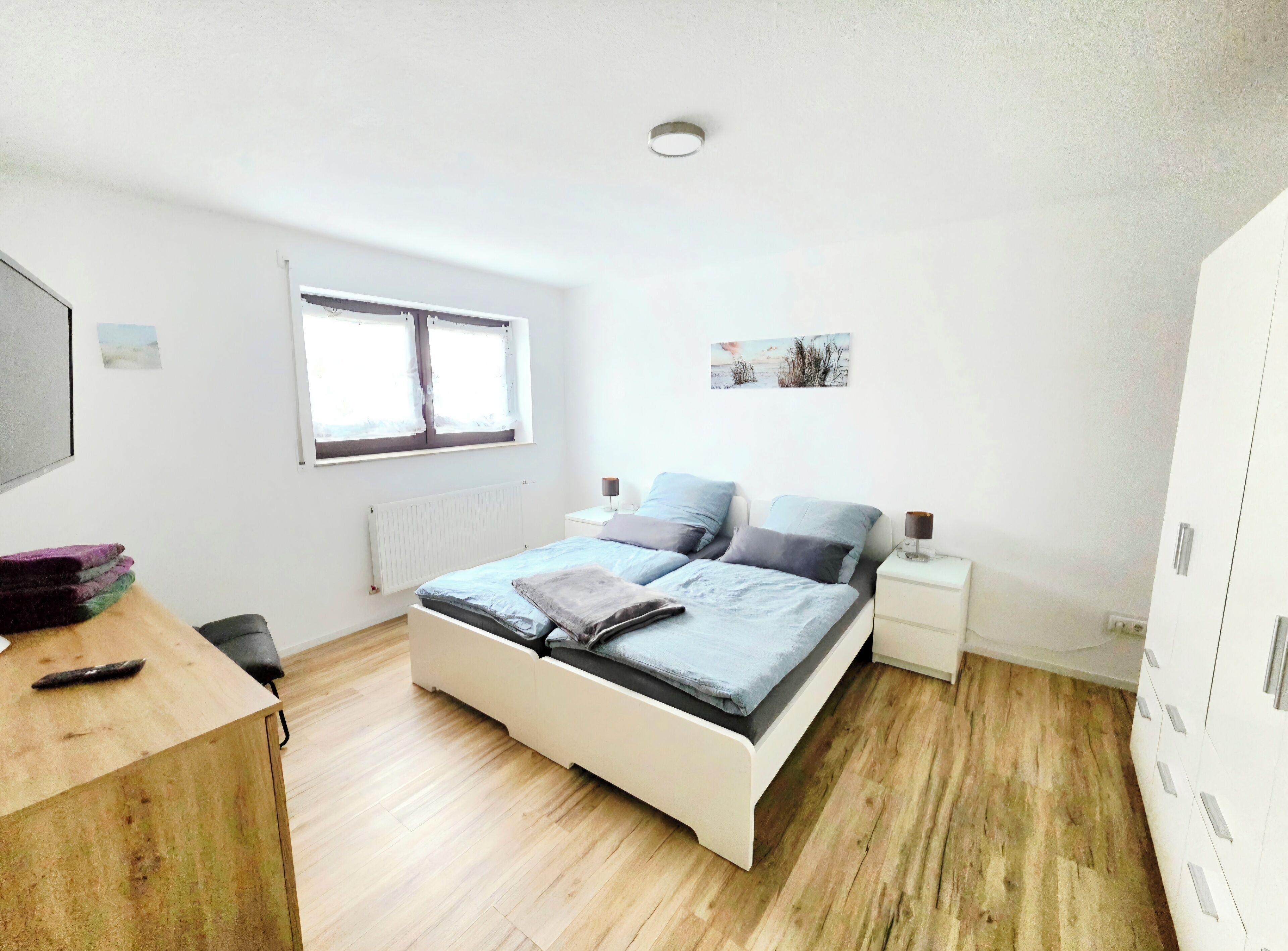 Ein Schlafzimmer mit Bett, Nachttischen, einem Schreibtisch und einem Fenster.