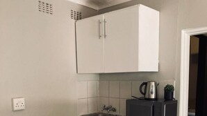 Eine Küche mit Holzausziehtisch, Spüle, Schränken und Wasserkocher auf der Arbeitsfläche.