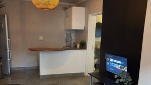 Eine moderne Küche mit einer runden Hängeleuchte, einem integrierten Fernseher und einer kleinen Sitzecke mit Teppich.