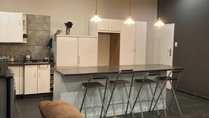 A modern kitchen with white cabinets, a central island with bar stools, and pendant lighting.