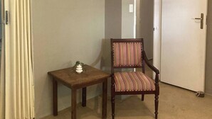 A room with a wooden chair, a small table, and a door.