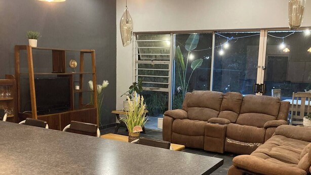 A modern kitchen with a central island, built-in cabinets, and a dining area with a brown leather sofa.