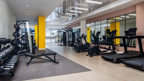 Ein modernes Fitnessstudio mit unterschiedlichen Trainingsgeräten, großen Fenstern und hellem Innenraum.
