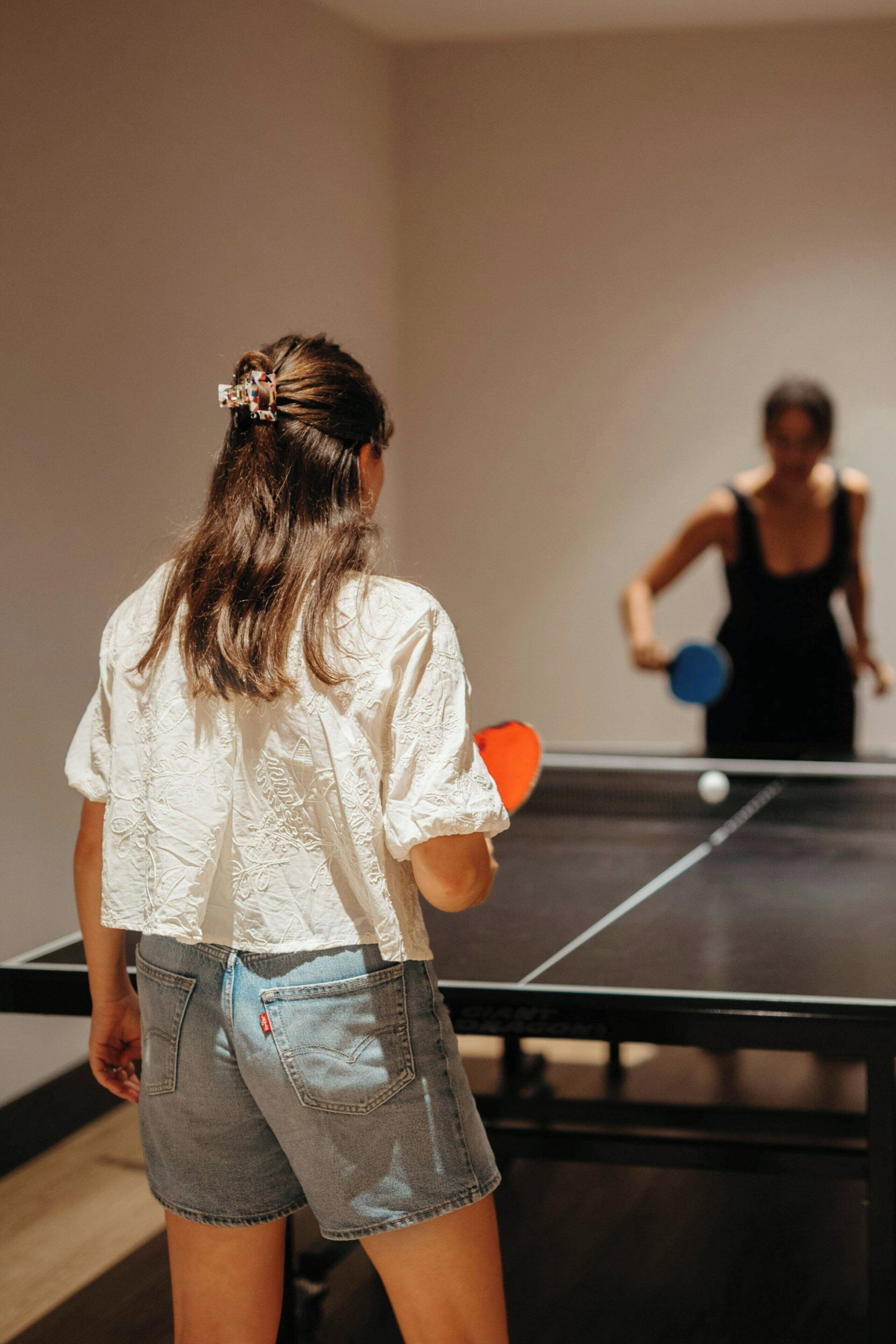 A person playing table tennis in a room with a ping pong table.