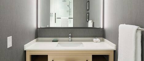 Un baño moderno con un espejo grande, un lavabo blanco y un perchero para toallas.