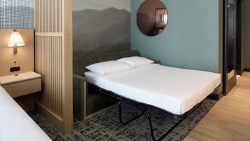 Una habitación de hotel moderna con una cama individual, una mesita de noche, una lámpara, un espejo y una alfombra estampada.