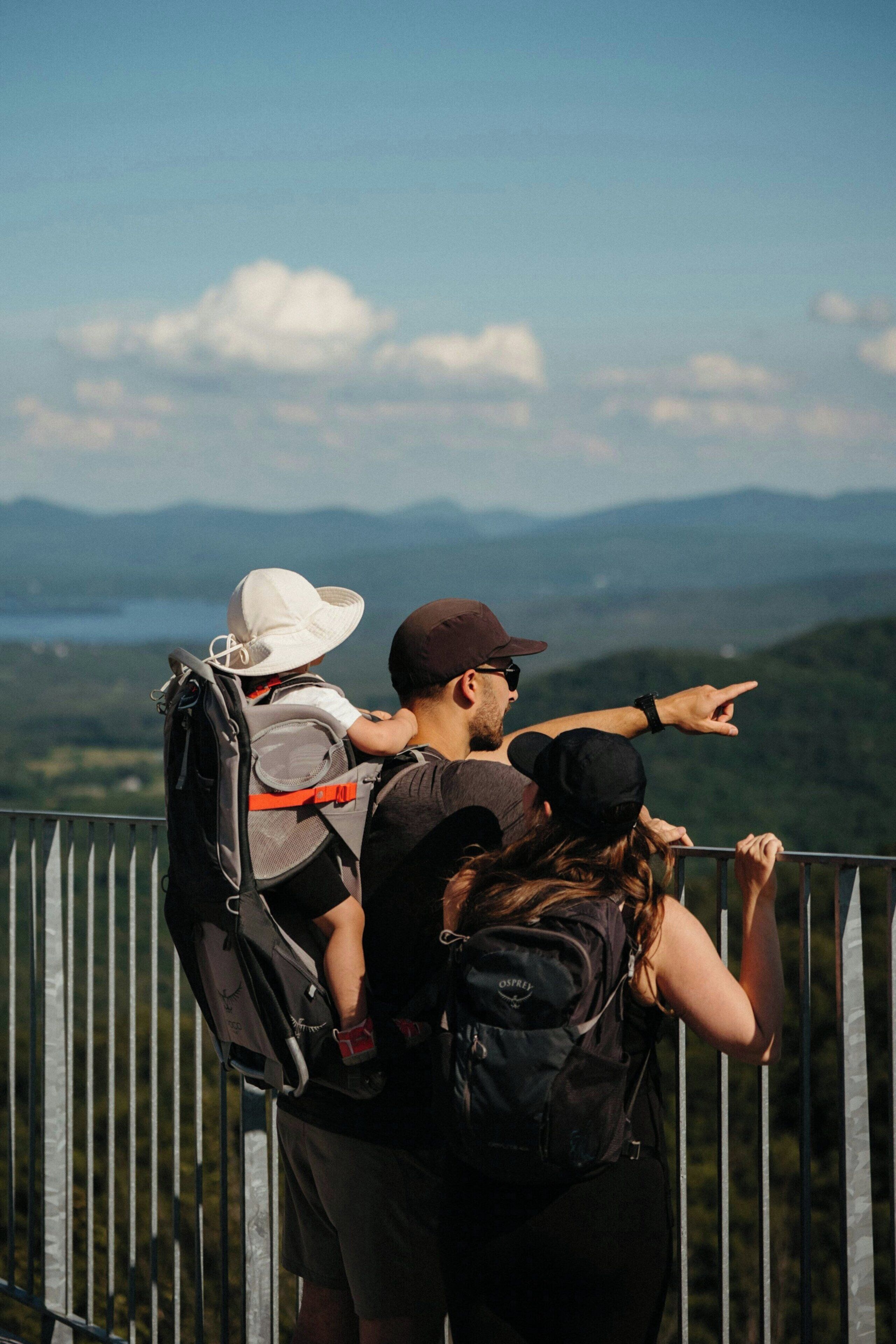 Una persona señala una vista panorámica con montañas y una masa de agua al fondo.