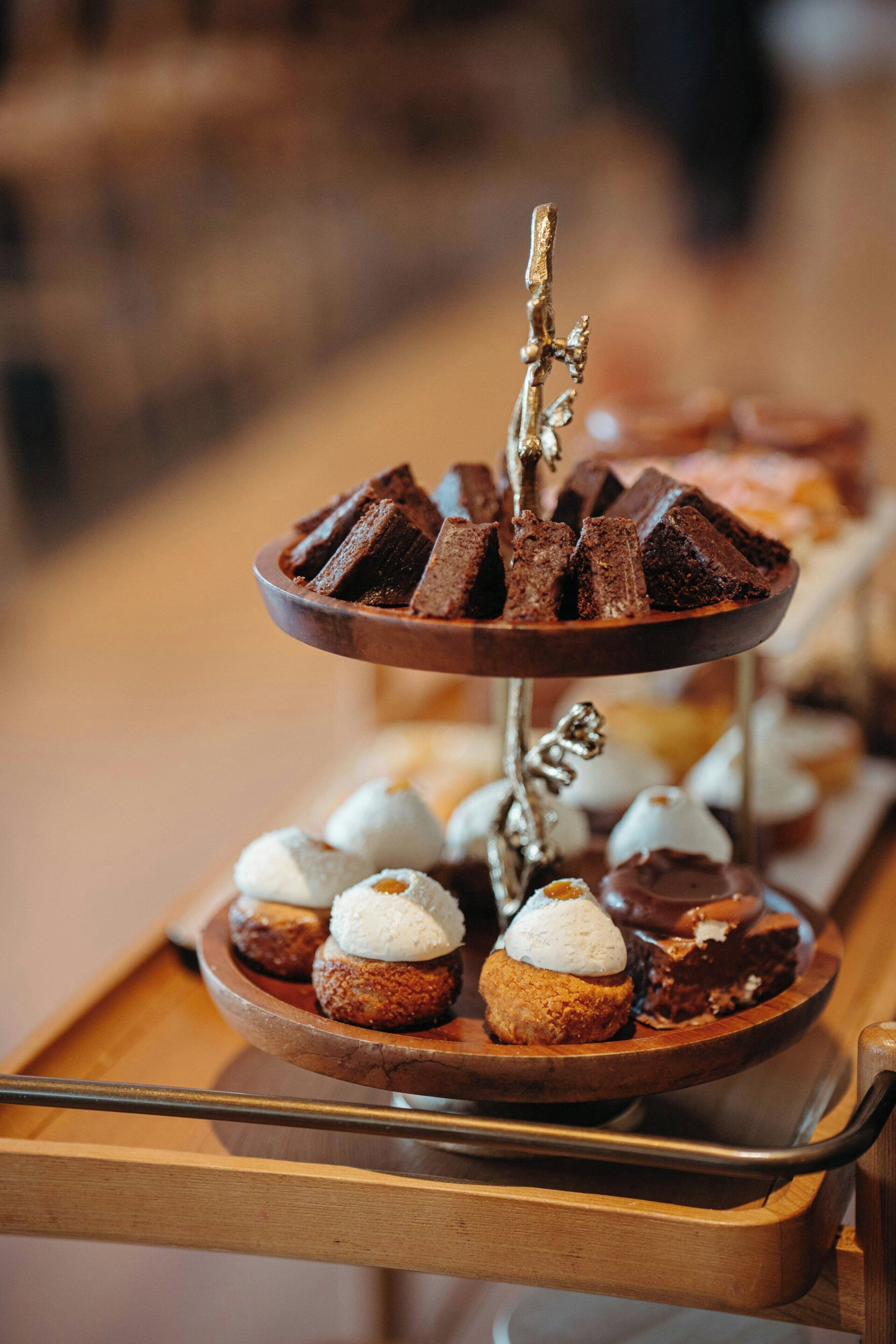 A dessert display with various sweets on a wooden tray.
