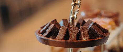 A dessert display with various sweets on a wooden tray.