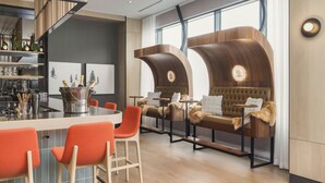 A modern interior with a bar area, seating with fur throws, and a large window providing natural light. - Residence Inn By Marriott Bromont (Bromont)