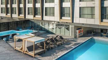 Una piscina al aire libre, sillones reclinables de piscina