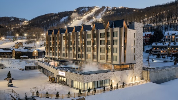 A hotel with multiple floors, a ski slope in the background, and a snow-covered landscape. - Residence Inn By Marriott Bromont (Bromont)