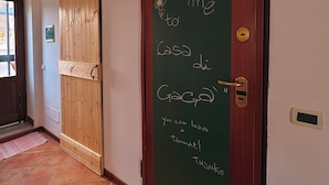 A hallway with a wooden door and a chalkboard with a welcome message. - Charming apartment with terrace in the heart of the Sicilian capital (Palermo)