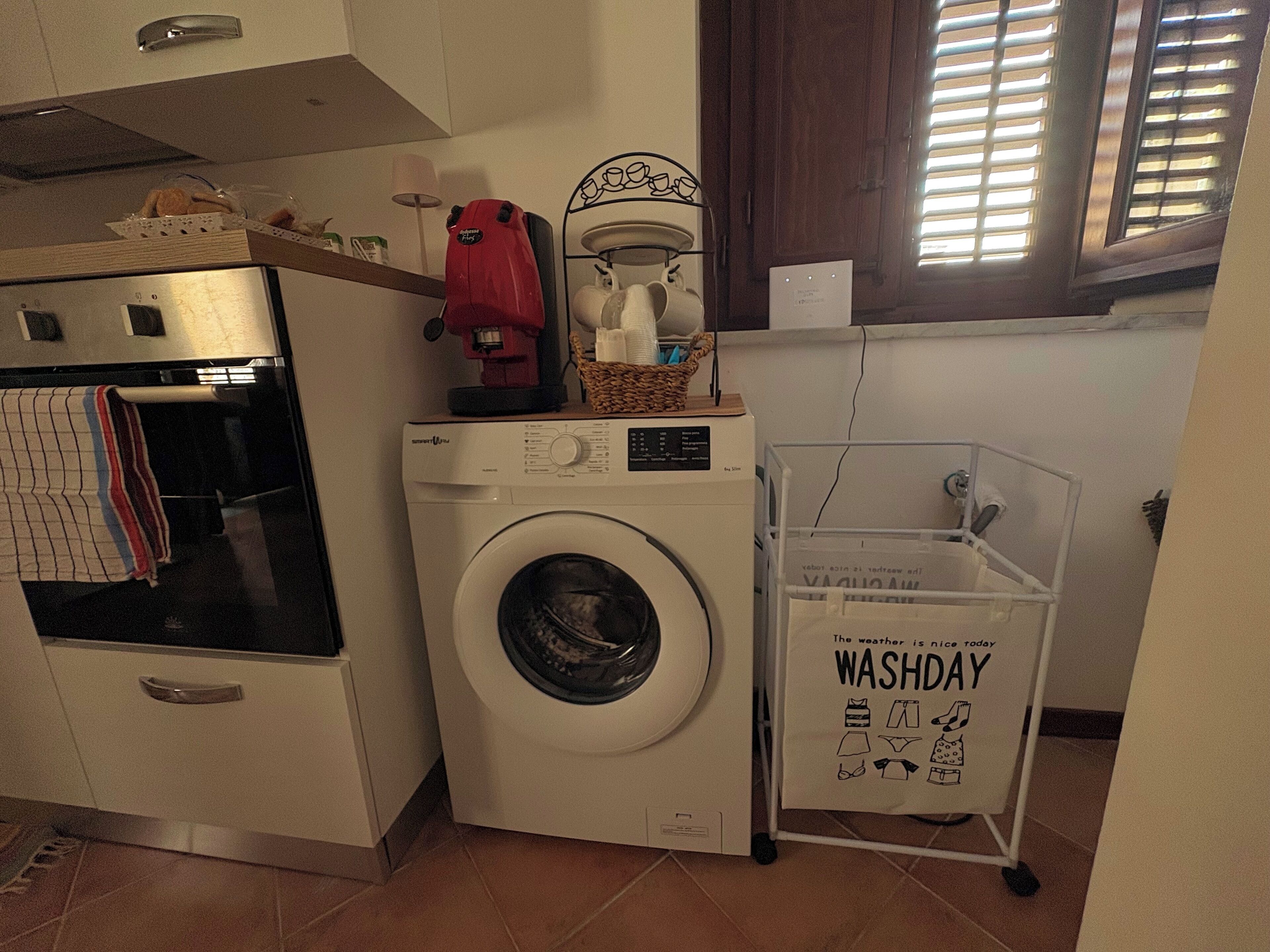 Een praktische wasruimte met een wasmachine, een droger en een klein plankje met een koffiezetapparaat.