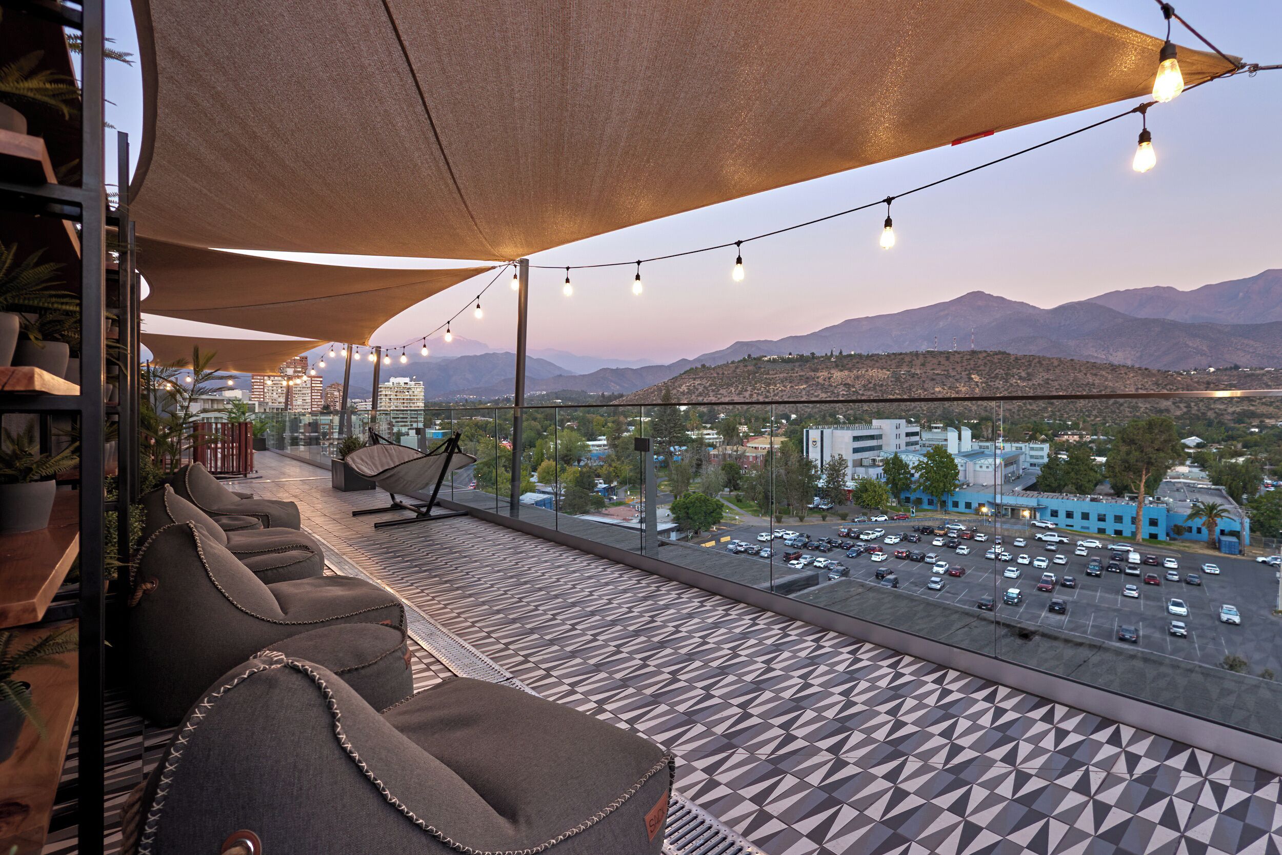 Une terrasse avec des sièges, une vue sur les montagnes et un parking.