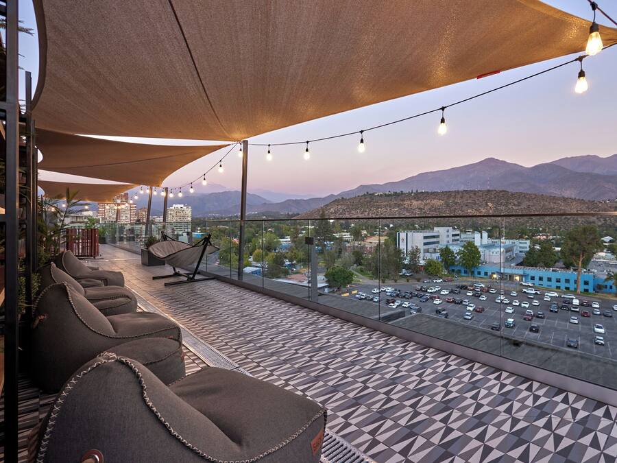 A terrace with seating, a view of mountains, and a parking lot.