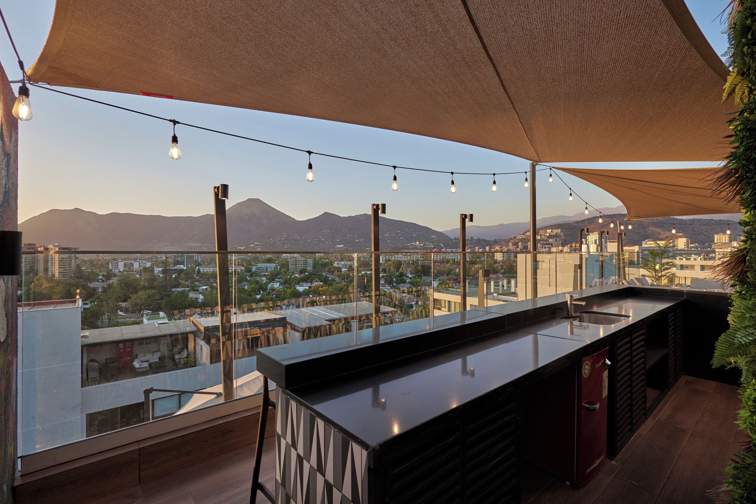 A rooftop bar with a view of a cityscape and mountains.