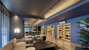 Een moderne lobby met zitplaatsen, een bijzettafeltje, een kamerplant en een boekenkast.